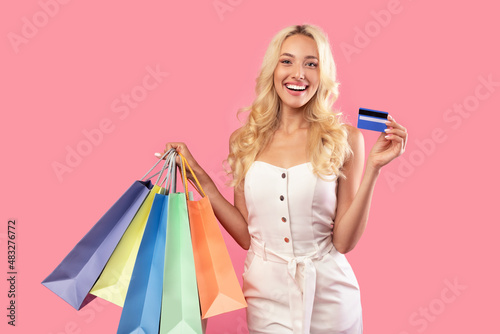 Happy woman holding credit card and colorful shopping bags
