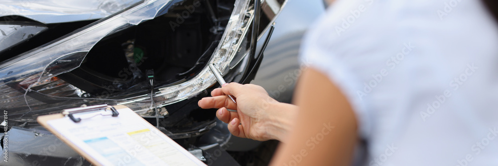 Insurance agent inspects damage to car after accident closeup
