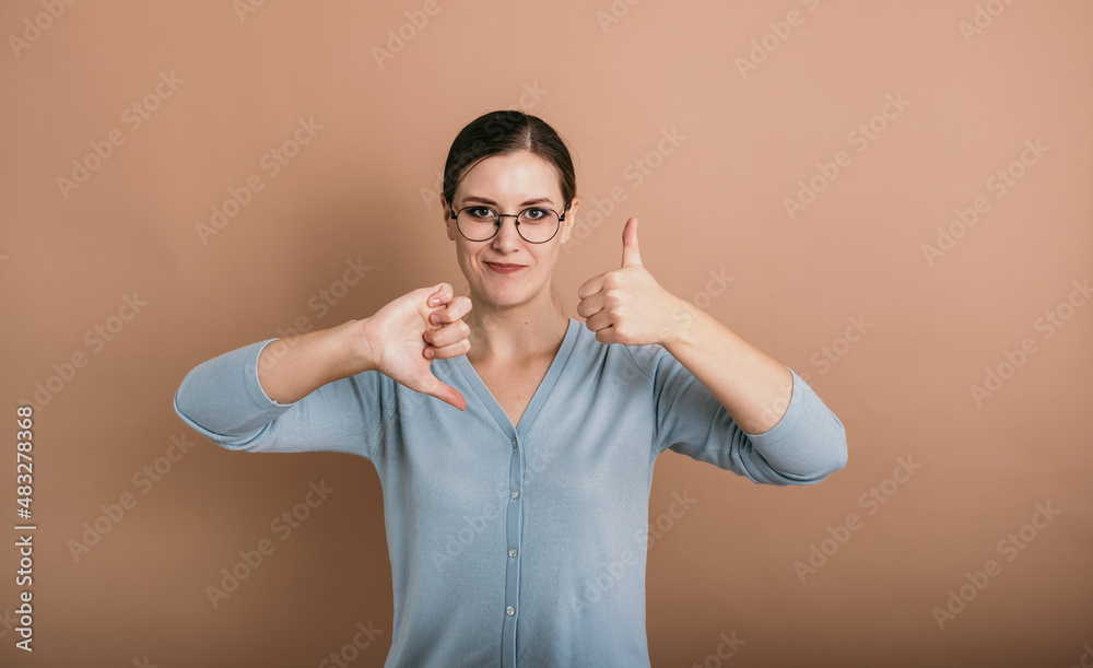 Φωτογραφία a brunette woman with glasses in a blue jumper stands and shows the signs bad an