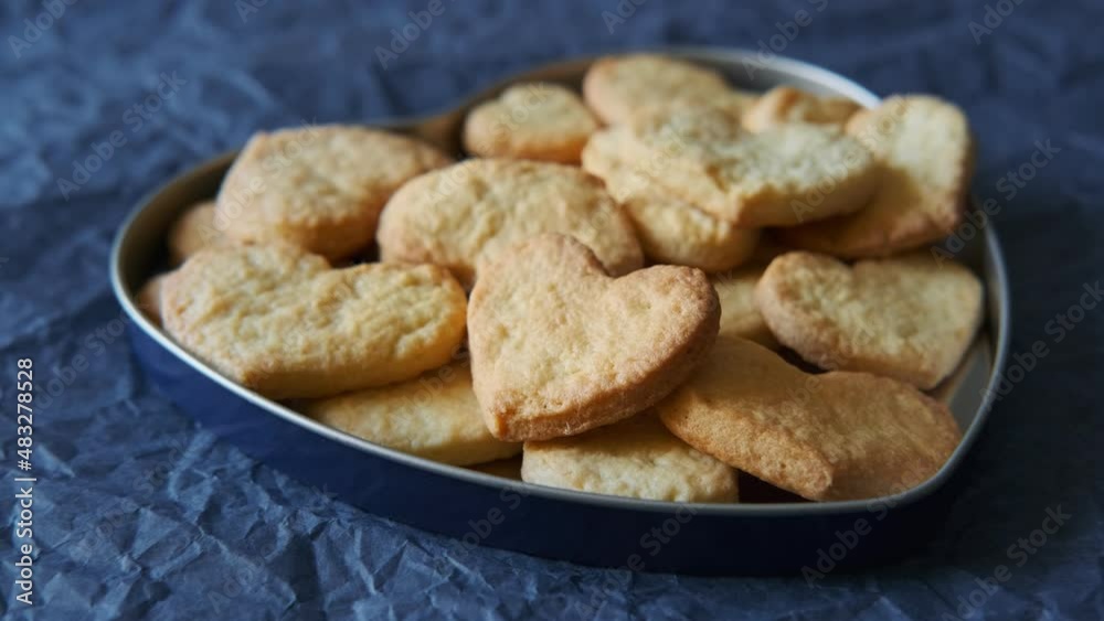 A Selection of Heart-Shaped Cookies Baked at Home and Arranged in a Heart-Shaped Tin Tray over a Blue, Tissue Paper Surface Closeup A Selection of Heart-Shaped Cookies Baked at Home and Arranged in a Heart-Shaped Tin Tray over a Blue, Tissue Paper Surface Closeup