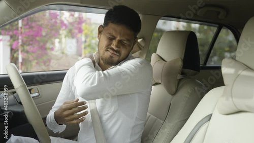 Tired young indian cab driver suffering from joint pain due to over driving - concept of arthritis, unhealthy lifestyle, overworked and exhusted. photo