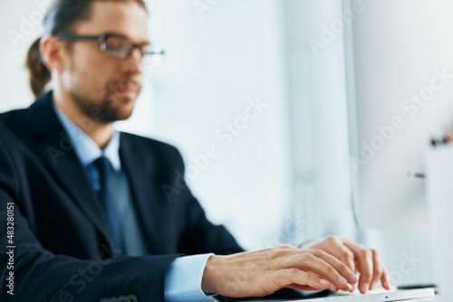 business man with glasses in a suit works at the computer in the office