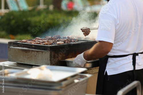 Metal construction for frying meat in nature, male chef do grill