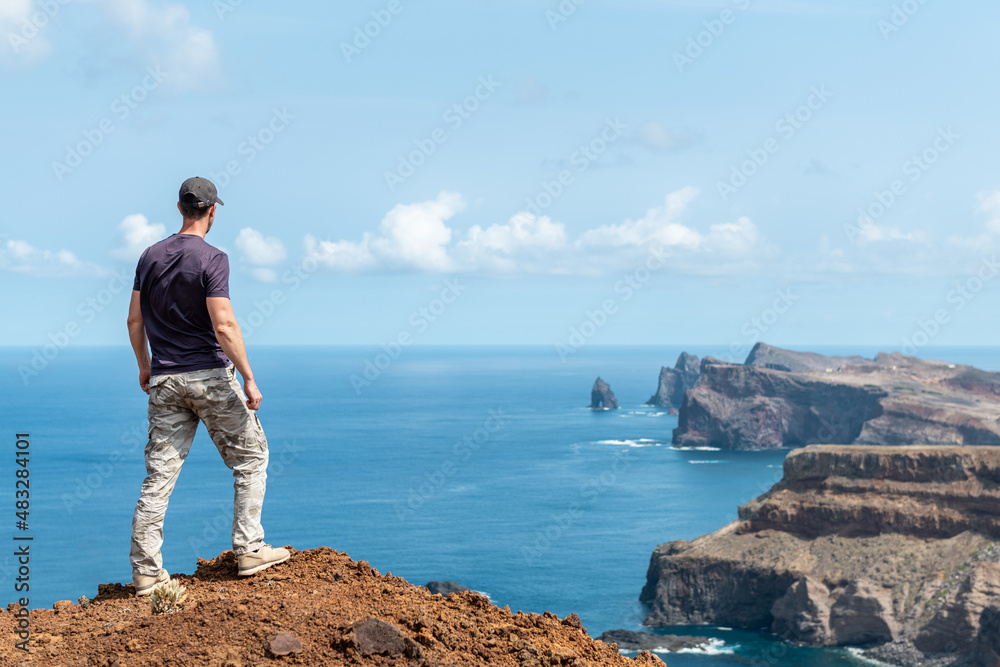 Mountain climber, man standing on top of mountain above ocean
