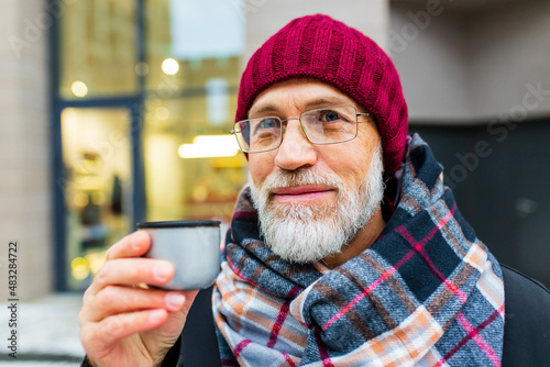 goog looking mature man drink hot tea in city street at winter
