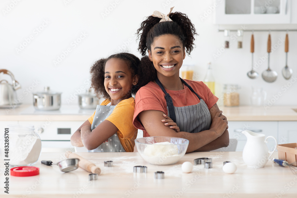 Cute african american mother and daughter posing while baking