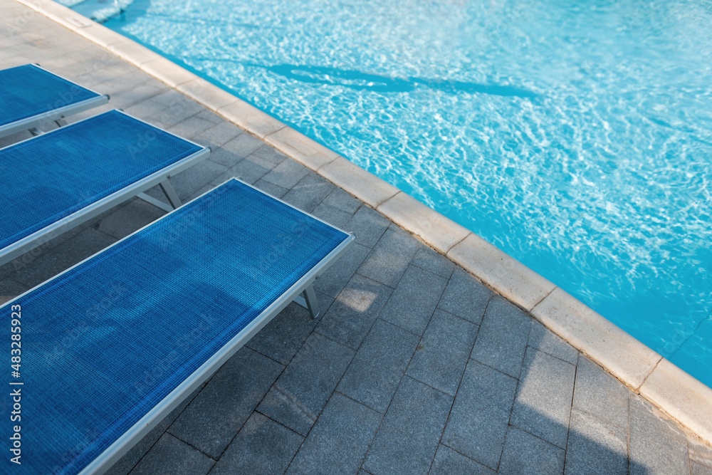 Beautiful blue swimming pool with sun loungers on a sunny warm summer day. Holidays and rest