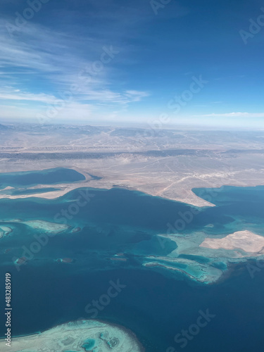 Nice view from the plane to the sea with islands, blue water, land, mountains and blue sky. Flight over Africa