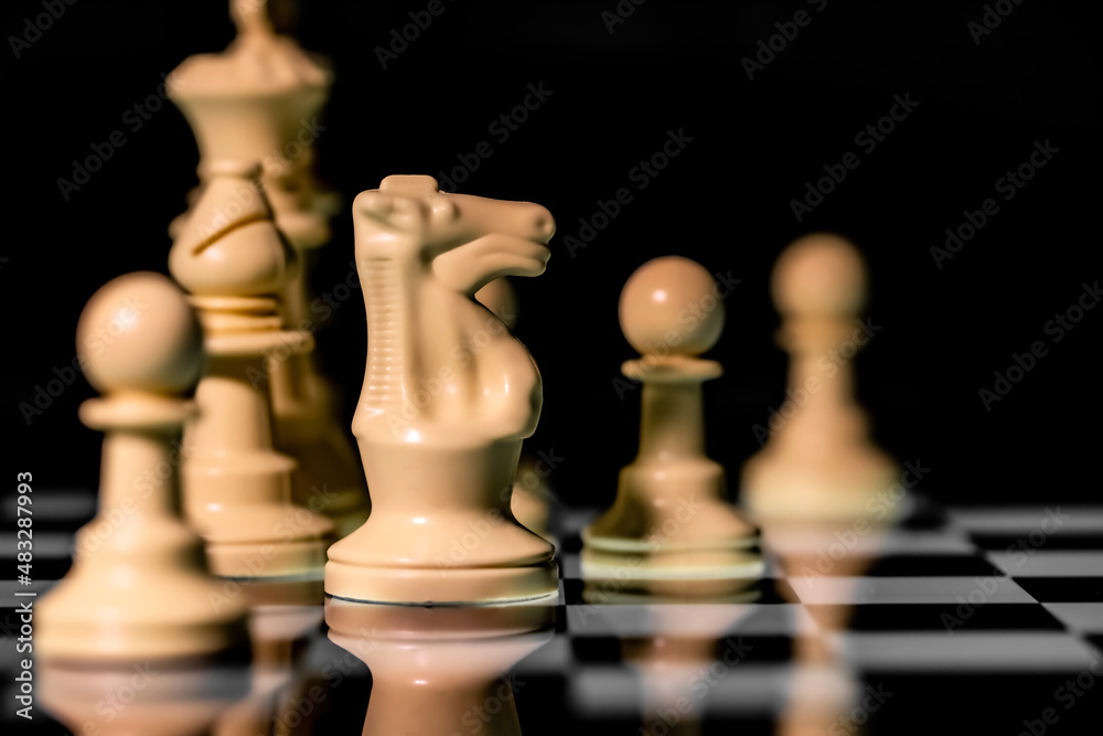 Close up of Chess pieces on a reflective mirror board surface with black background Close up of Chess pieces on a reflective mirror board surface with black background