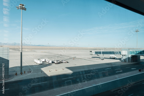 Beautiful airport with cars, a boarding bridge and an empty runway against the backdrop of mountains, desert and blue sky. Travel by plane concept. Pandemic and airlines