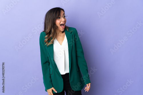 Young caucasian woman isolated on purple background doing surprise gesture while looking to the side