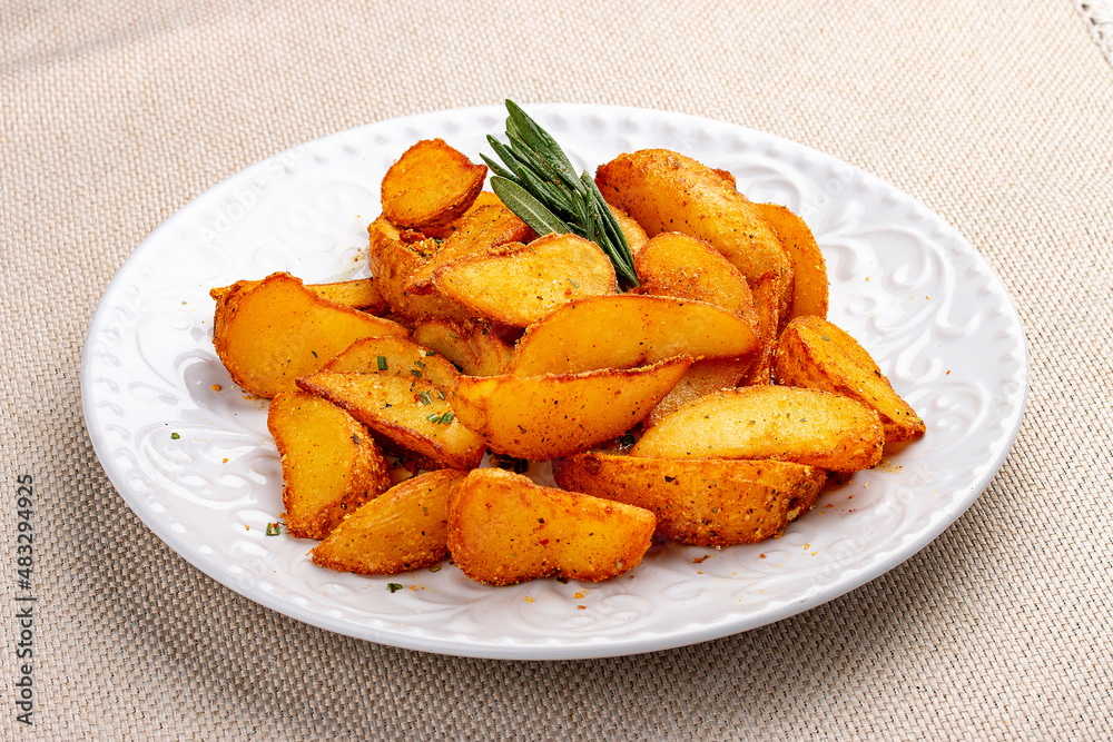 Sliced fried potatoes, Creole-style with spices. On a white plate. Sliced fried potatoes, Creole-style with spices. On a white plate.
