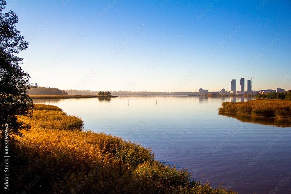Calm sunny autumn morning with city skyline reflected in water