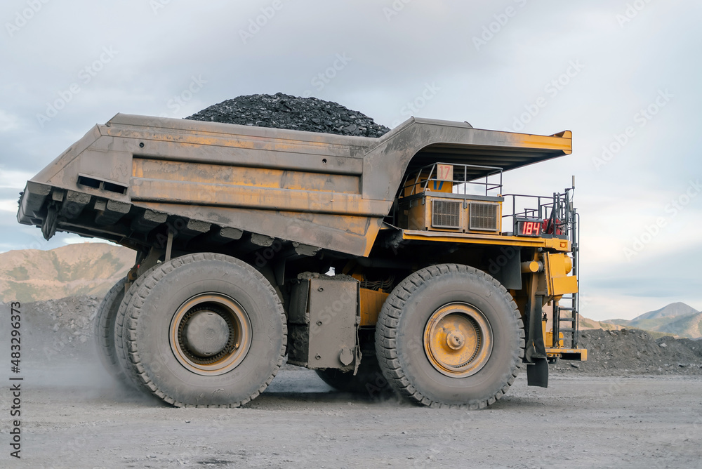 A dump truck loaded with ore drives through an open pit. A dump truck loaded with ore drives through an open pit.