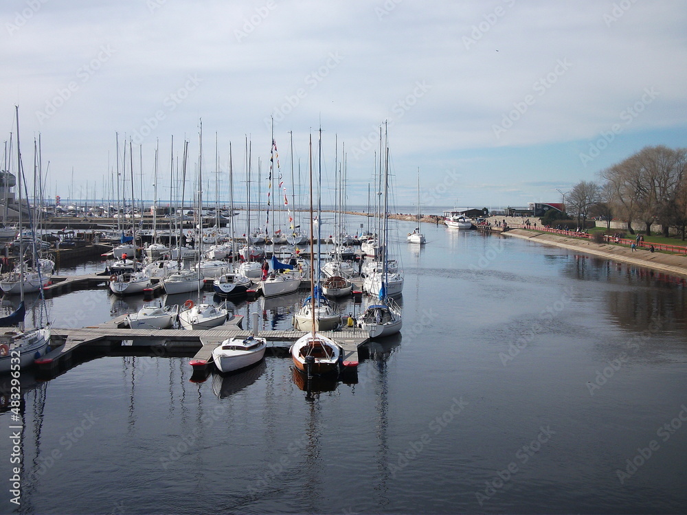 View of the yacht club. The yachts are moored at the pier and reflected in the sea. Early morning.