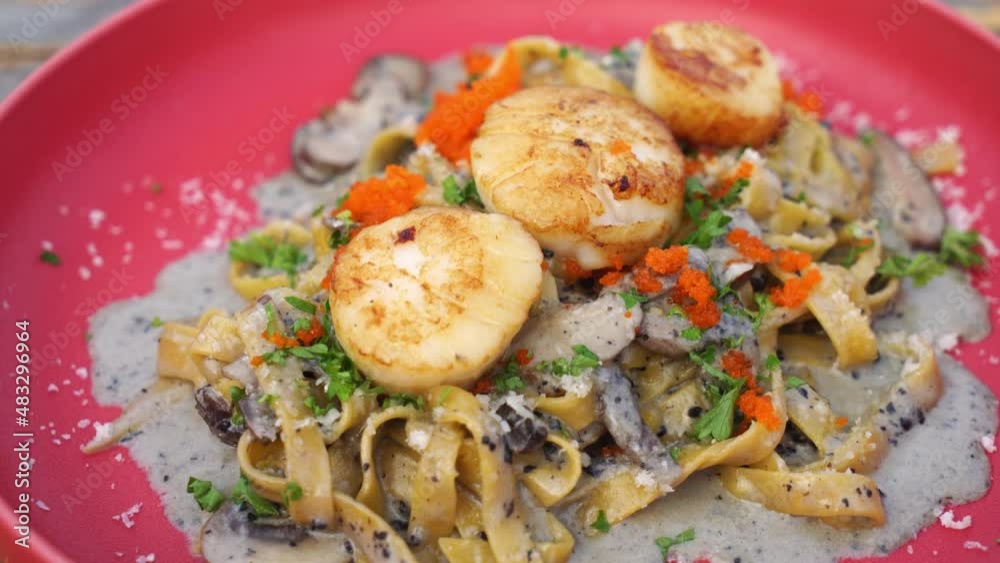fettuccini spaghetti with scallop truffle cream sauce on red plate fettuccini spaghetti with scallop truffle cream sauce on red plate