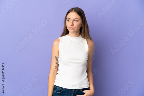 Young Lithuanian woman isolated on purple background having doubts while looking side