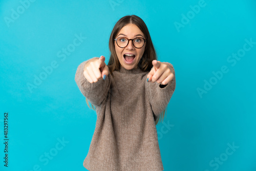 Young Lithuanian woman isolated on blue background surprised and pointing front photo