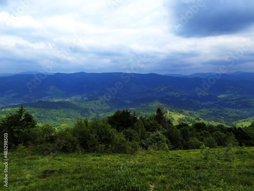 Green summer mountain landscape. A meadow on the top of the mountain. Mountain ranges on the horizon.