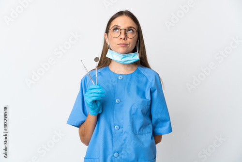 Lithuanian woman dentist holding tools over isolated background and looking up