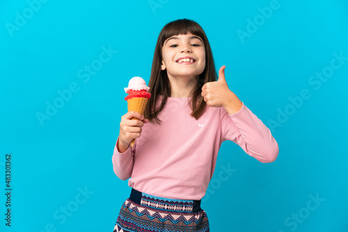 Little girl with a cornet ice cream isolated on blue background giving a thumbs up gesture