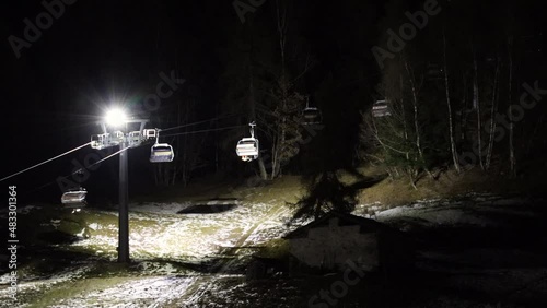 Chairlifts in he night, under the light of a headlight, moving steadily uphill. Italian ski district of Aprica, in Valtellina. Italian alps. 