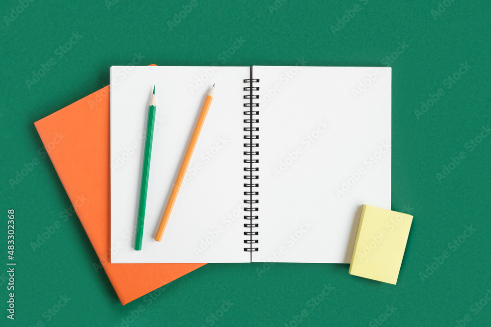 Notebook with pencil. Open notebook on dark green color background, spiral notepad on table. Top view of open notepad with blank pages, office flat lay. White Page for your write. Copy Space Notebook with pencil. Open notebook on dark green color background, spiral notepad on table. Top view of open notepad with blank pages, office flat lay. White Page for your write. Copy Space