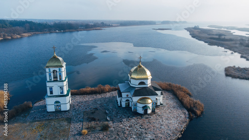 Aerial view of the old Church of the Transfiguration with a bell tower on the island of the Kanev reservoir, the flooded village of Gusintsy, Rzhishchev, Ukraine. photo