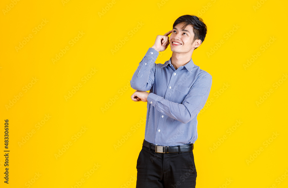 Portrait studio shot of millennial Asian young male professional successful businessman entrepreneur in formal shirt and slacks standing posing on yellow background. Portrait studio shot of millennial Asian young male professional successful businessman entrepreneur in formal shirt and slacks standing posing on yellow background.