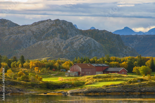 small farm on a norwegian fjord with mountain backdrop