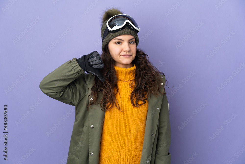 Teenager Russian girl with snowboarding glasses isolated on purple background showing thumb down with negative expression Teenager Russian girl with snowboarding glasses isolated on purple background showing thumb down with negative expression