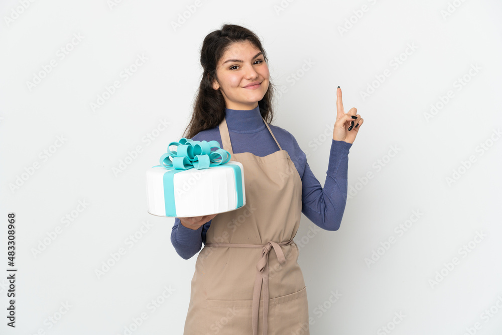 Pastry Russian chef holding a big cake isolated on white background showing and lifting a finger in sign of the best Pastry Russian chef holding a big cake isolated on white background showing and lifting a finger in sign of the best