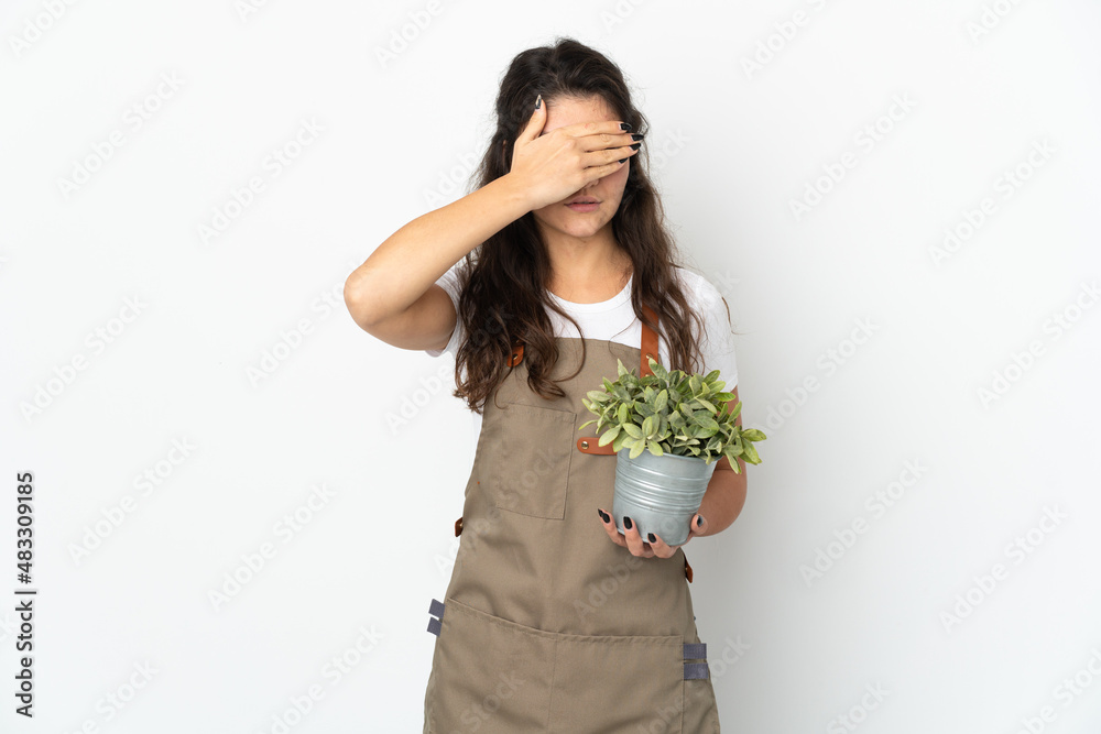 Young Russian gardener girl holding a plant isolated covering eyes by hands. Do not want to see something Young Russian gardener girl holding a plant isolated covering eyes by hands. Do not want to see something