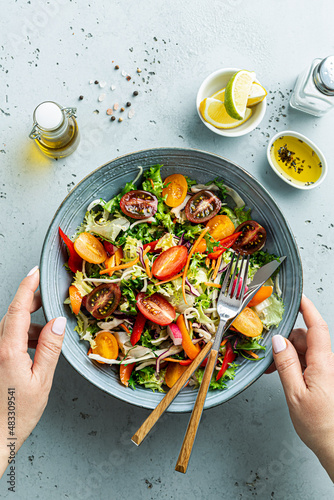 Woman’s hands holding bowl with fresh colorful spring vegetable salad - lunch