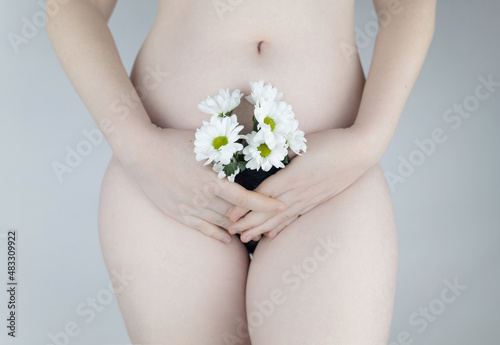 Close-up of a woman body. Female pubis. Panties from which flowers stick out. Concept photo about feminine intimate health. Delicate and sensual frame without a hint of eroticism. Selective focus. photo