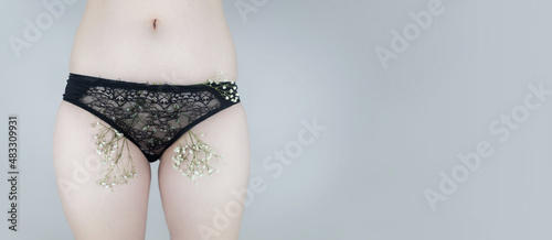 A woman has small flowers sticking out from under her underpants, imitating extra hair. Laser hair removal and shaving with a razor. Conceptual shot about women issues. Proper self care. photo