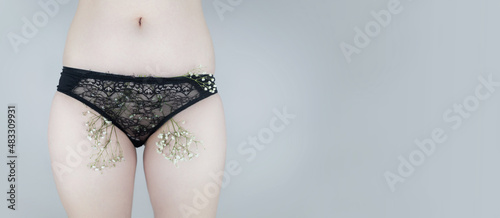 A woman has small flowers sticking out from under her underpants, imitating extra hair. Laser hair removal and shaving with a razor. Conceptual shot about women issues. Proper self care.