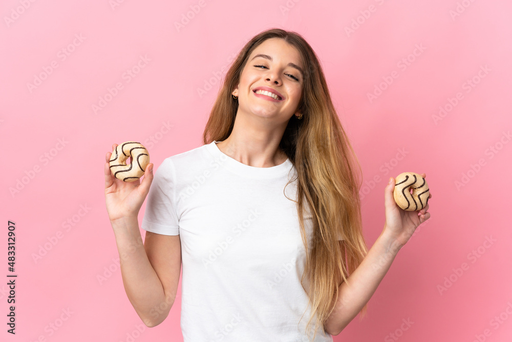 Young blonde woman isolated on pink background holding a donut and happy Young blonde woman isolated on pink background holding a donut and happy