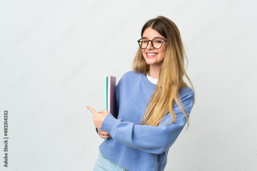 Young blonde student woman isolated on white background pointing back Young blonde student woman isolated on white background pointing back