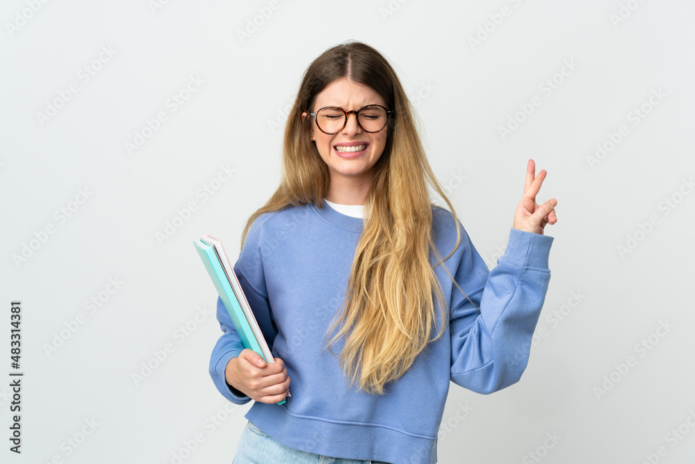 Young blonde student woman isolated on white background with fingers crossing and wishing the best Young blonde student woman isolated on white background with fingers crossing and wishing the best