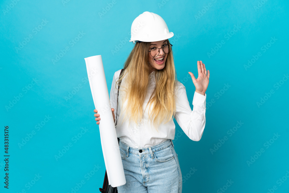 Young architect woman with helmet and holding blueprints isolated on blue background saluting with hand with happy expression Young architect woman with helmet and holding blueprints isolated on blue background saluting with hand with happy expression