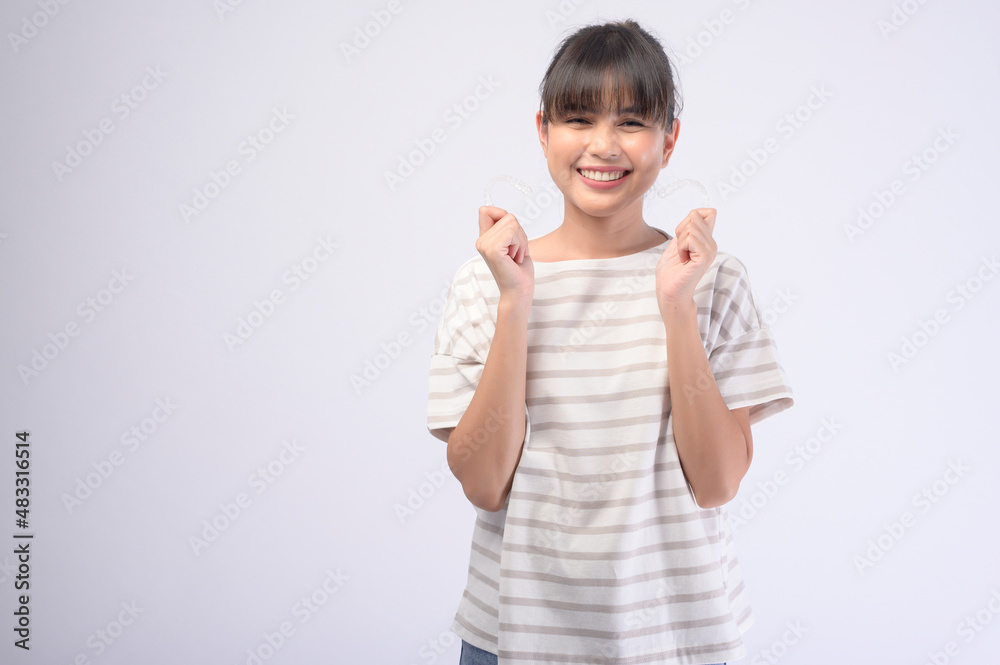 Young smiling woman holding invisalign braces over white background studio, dental healthcare and Orthodontic concept. Young smiling woman holding invisalign braces over white background studio, dental healthcare and Orthodontic concept.