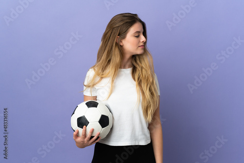 Young blonde football player woman isolated on purple background looking to the side © luismolinero