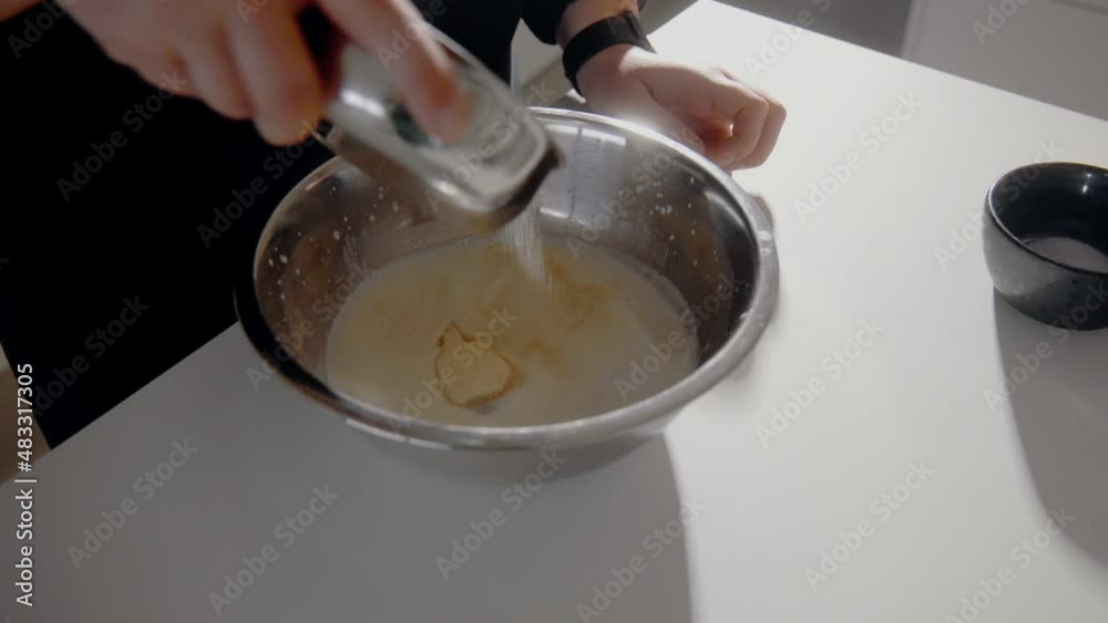 Young Female pouring sugar in a bowl with milk and eggs making dough for a cake in the kitchen at home. Homemade pastry close up Young Female pouring sugar in a bowl with milk and eggs making dough for a cake in the kitchen at home. Homemade pastry close up