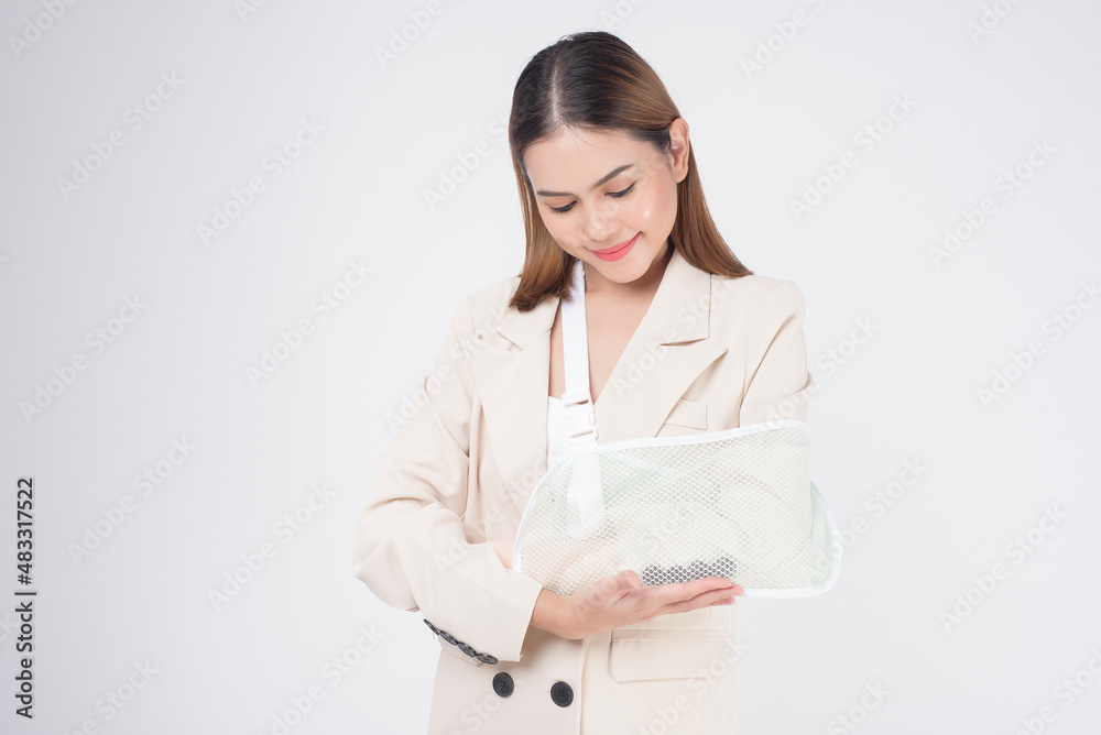 Portrait of young woman with an injured arm in a sling over white background in studio.. Portrait of young woman with an injured arm in a sling over white background in studio..
