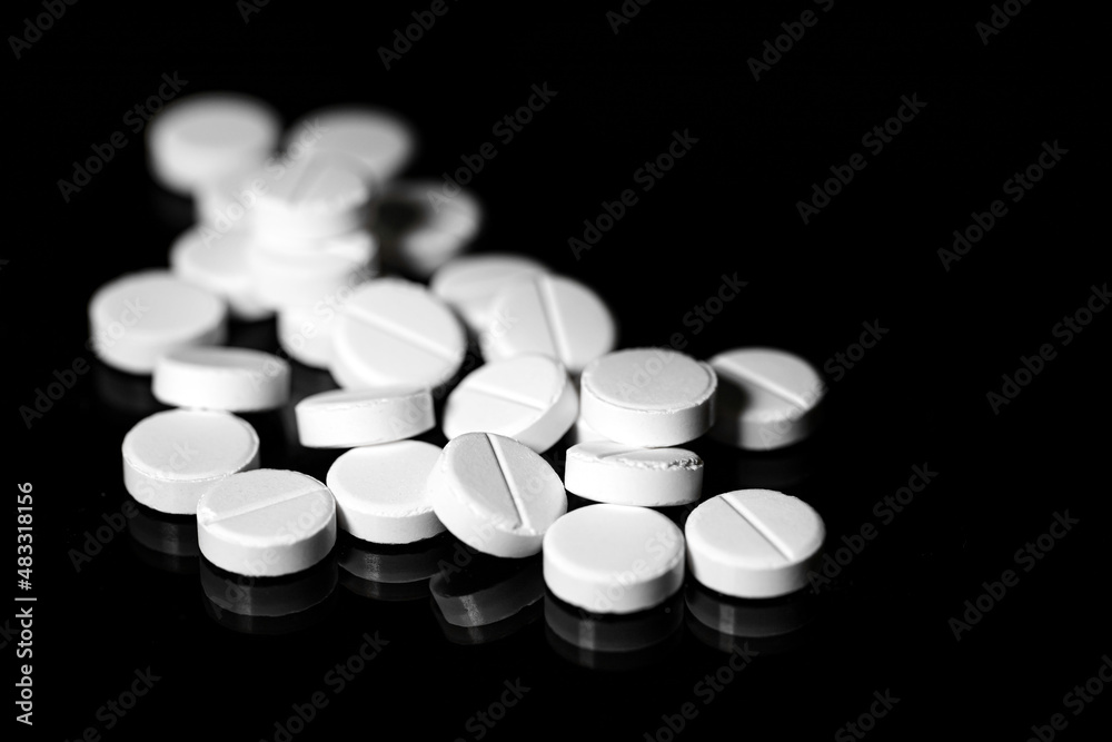 Close up of white painkiller tablet on a reflective black background Close up of white painkiller tablet on a reflective black background