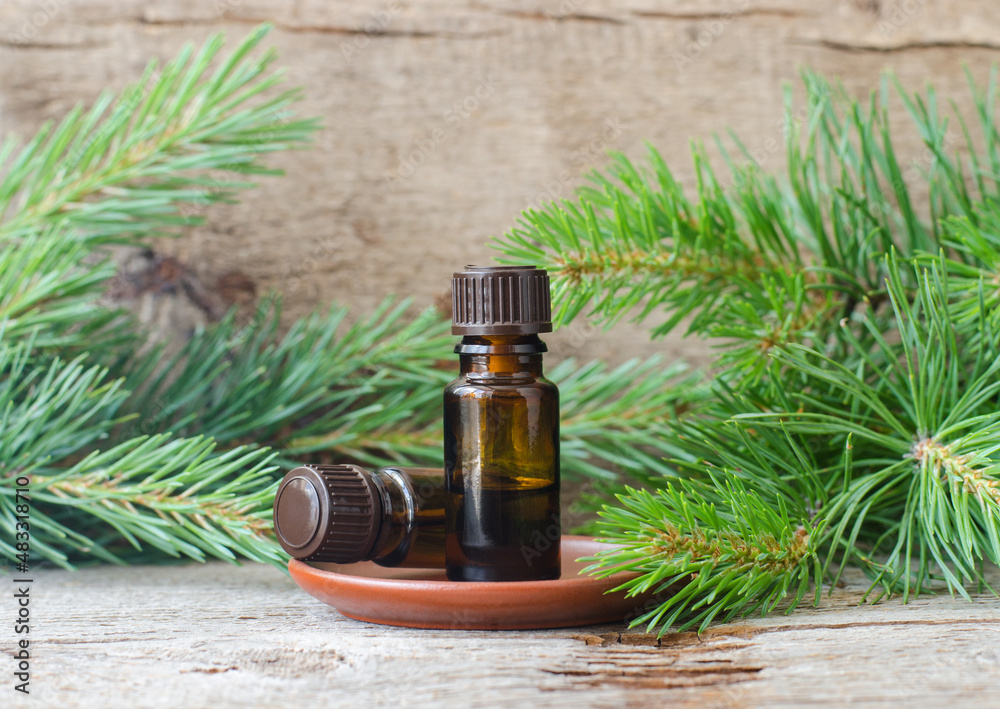 Fototapeta premium Small glass bottles with essential pine oil. Aromatherapy, sauna, homemade spa and herbal medicine ingredients. Old wooden background. Copy space.