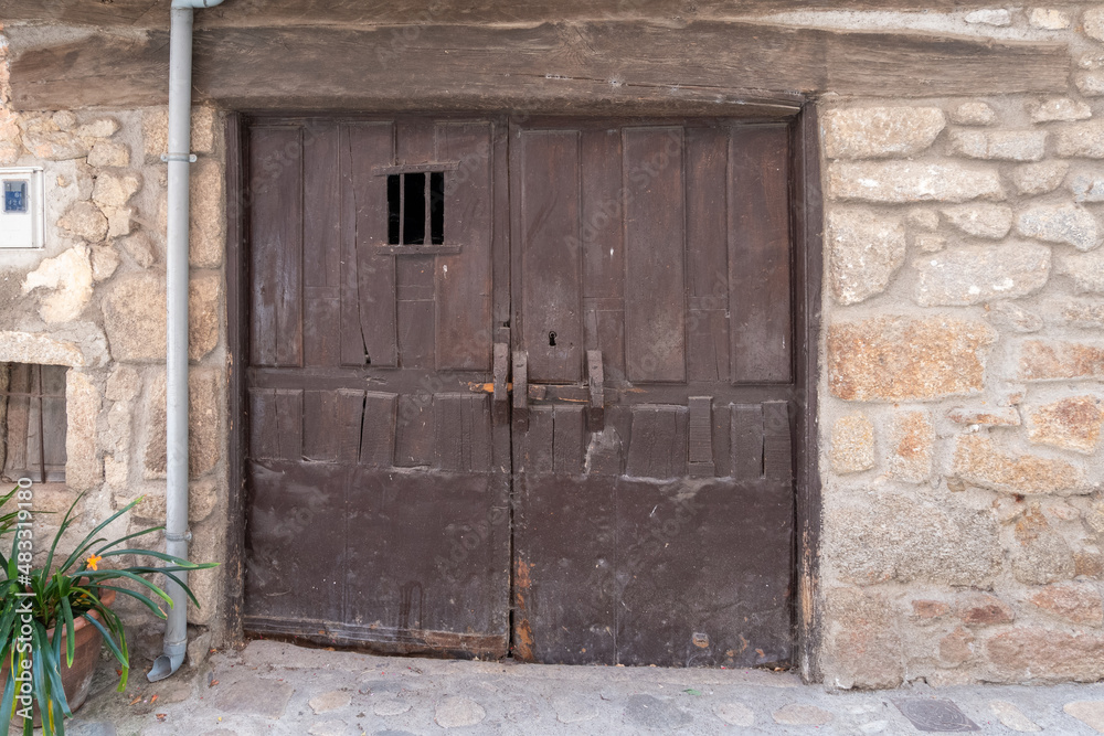 Entrance to an old stable with stone walls with an old two-leaf door Entrance to an old stable with stone walls with an old two-leaf door