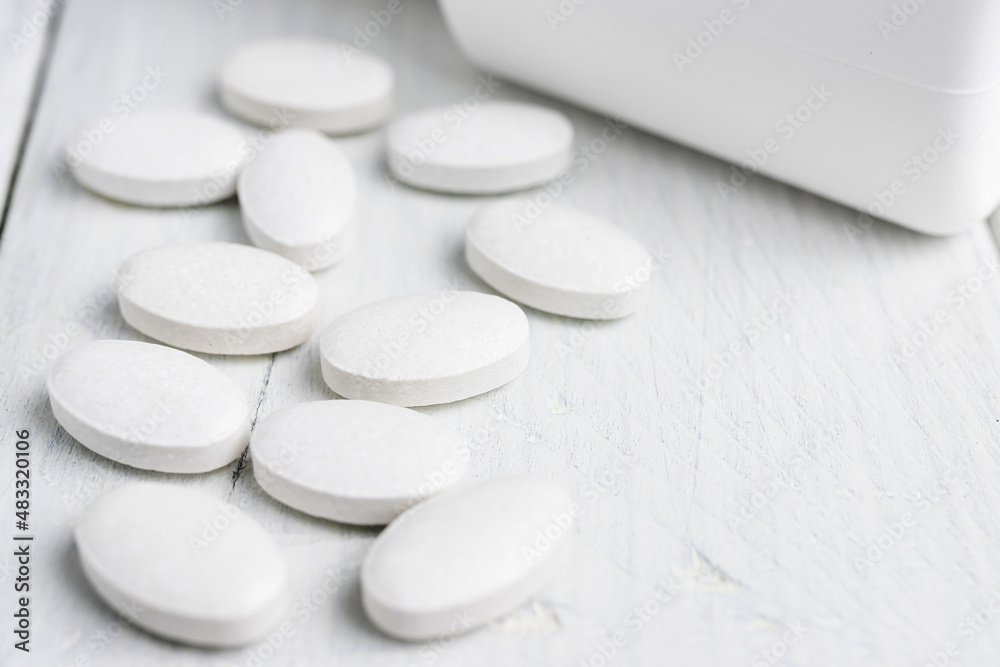 White pills at white wooden planks, medication treatment, close-up view White pills at white wooden planks, medication treatment, close-up view