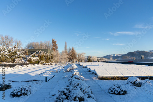 snow on solar modules on a roof top in sunrise sunlight under blueskys with small clouds